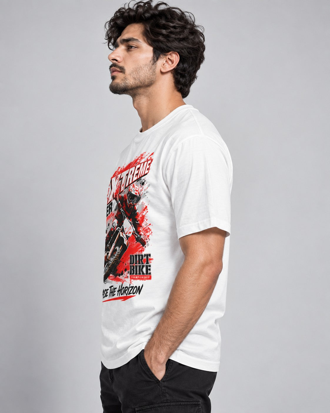 Side profile view of a male model wearing a white dirt bike graphic printed t-shirt with black cargo pants.
