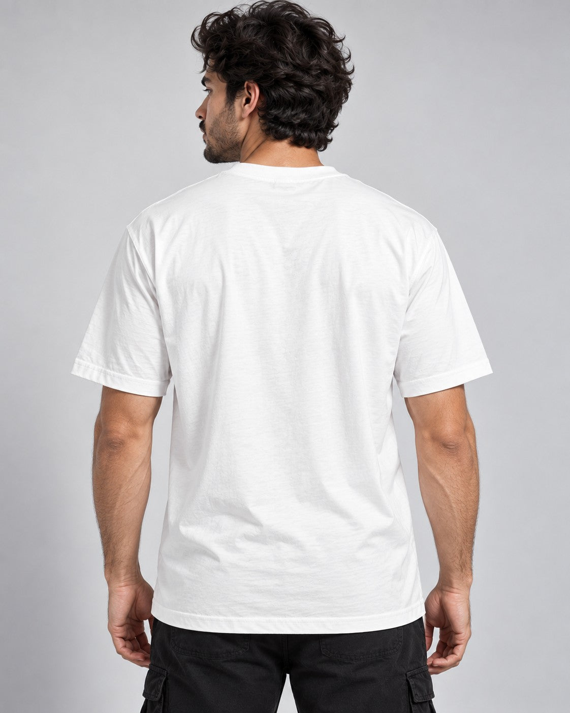 Back view of a male model wearing a plain white oversized t-shirt paired with black cargo pants.